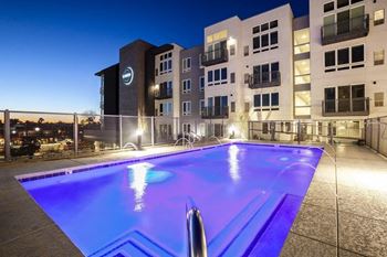 A swimming pool in front of an apartment building at night